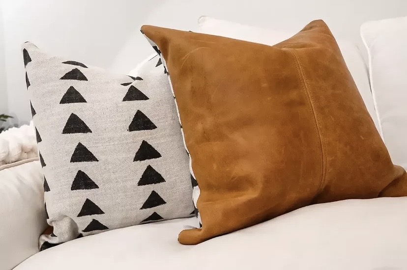 Tan leather scatter cushion paired with a mudcloth triangle-print cushion